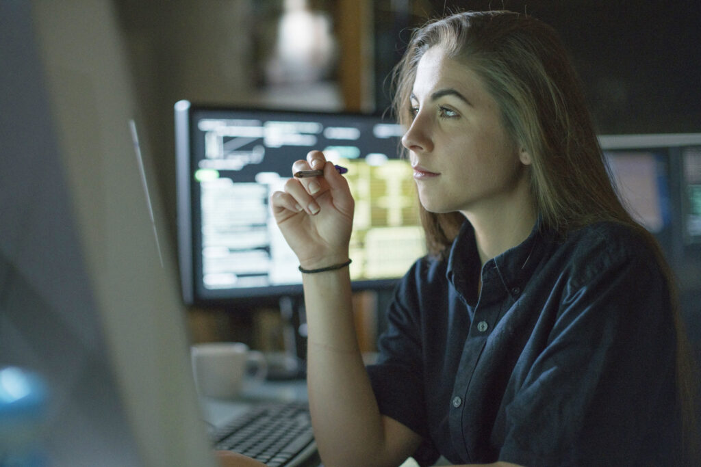 En ung kvinde sidder ved et skrivebord og kigger på en skærm.