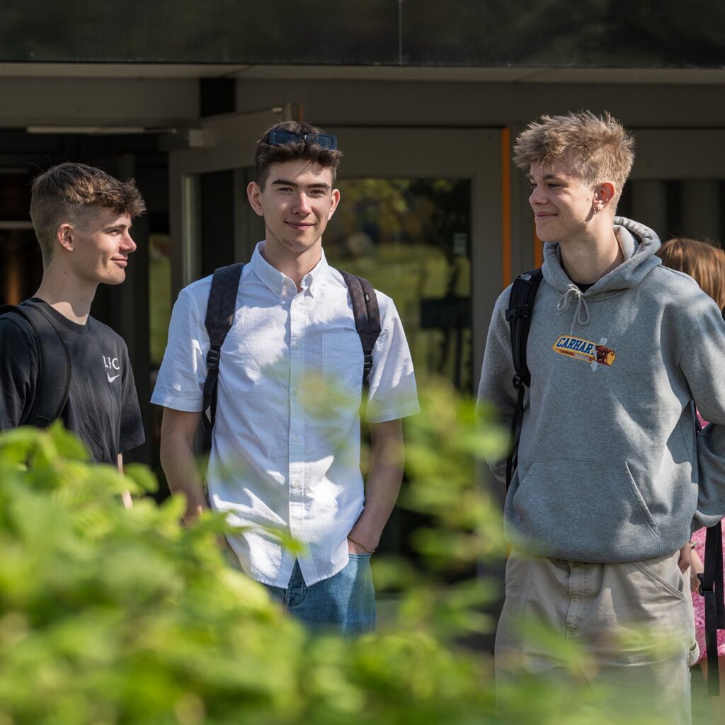 Tre elever fra NEG Kalundborg står ude foran skolen i det gode vejr.