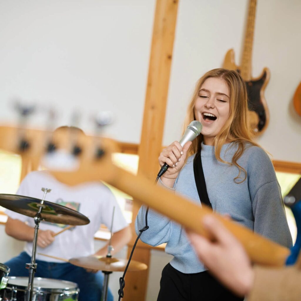 Elev fra NEG Kalundborg står og synger ind i en mikrofon. Hun står sammen med et band.