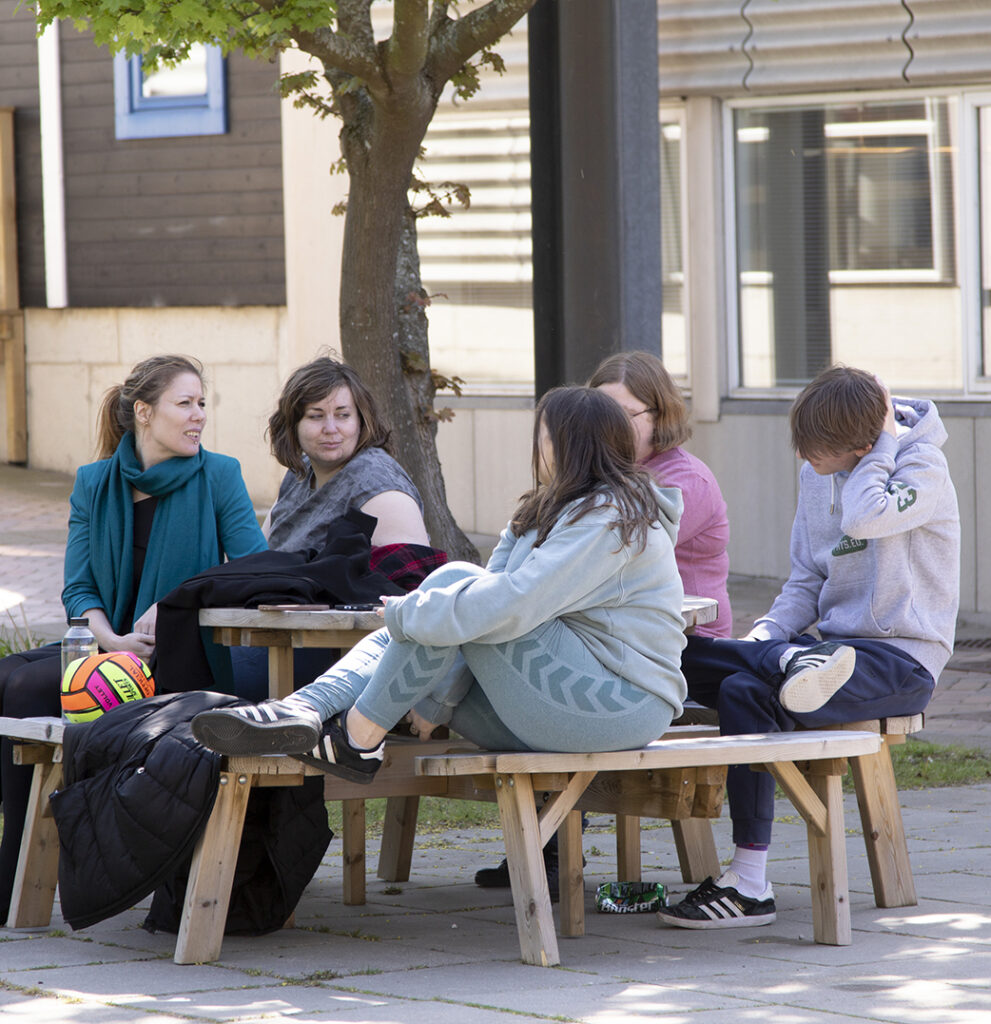 Fem elever fra NEG Kalundborg sidder udenfor sammen. De sidder ved et borde bænkesæt.
